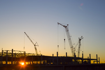 Construction cranes at sunset.