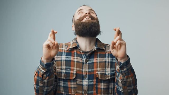 Hipster bearded man standing with fingers crossed for good luck
