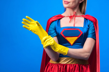cropped shot of woman in superhero costume wearing rubber gloves isolated on blue