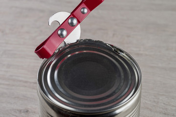 Opening a tin can with a can opener.
