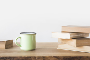 green cup and books on wooden table on white