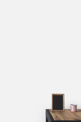 empty blackboard in frame with cup on wooden table on white