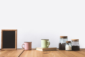 cups with book and glass bottles with coffee beans and refined sugar and blackboard