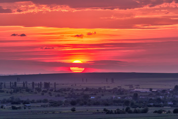 Beautiful rural landscape with a big red setting sun over the fields, Dobrogea, Romania