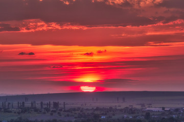 Fototapeta premium Beautiful rural landscape with a big red setting sun over the fields, Dobrogea, Romania