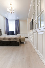 Спальня в светлых тонах с темной кроватью и синими шторами