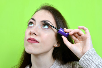 Girl applying mascara on her eyelashes.