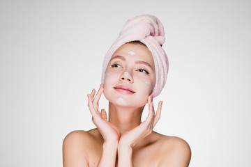 happy woman with a towel on her head applied a face cream