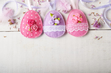 Handmade patchwork pink and lilac felt easter eggs on white wooden table