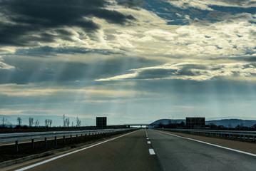 Two line wide highway on a cloudy winter day leading to the mountains through rural landscape