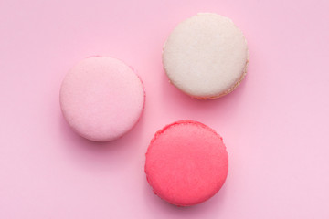 Top view of mini pink and white macaron on soft sweet pink paper background
