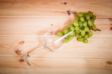 Empty wine glass with green grape on wooden background