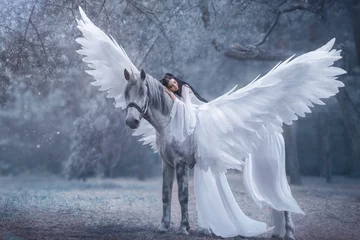 Papier Peint photo Femme Princesse de femme fantastique. Belle jeune elfe marchant avec une licorne. Elle porte une incroyable robe blanche légère. La fille est allongée sur le cheval pégase. La belle au bois dormant. Photographie Artistique