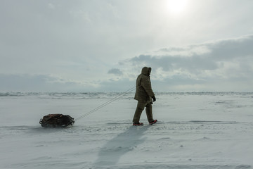 Woman with a sledge walk is on the ice of Lake Baikal