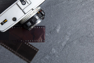 Vintage camera and film negatives on a slate background