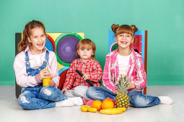 Three children watch tv and eat fruits. The concept of a healthy lifestyle, food, childhood, vitamins, vegetarianism.