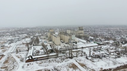Grain terminal in the winter season. Snow-covered grain elevator in rural areas. A building for drying and storing grain