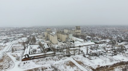 Grain terminal in the winter season. Snow-covered grain elevator in rural areas. A building for drying and storing grain