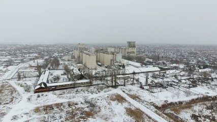 Naklejka premium Grain terminal in the winter season. Snow-covered grain elevator in rural areas. A building for drying and storing grain