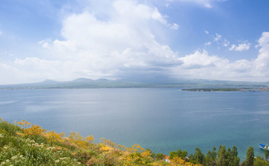 Fototapeta na wymiar Lake Sevan in Armenia. View of the lake, the horizon and clouds. Yellow wildflowers. 