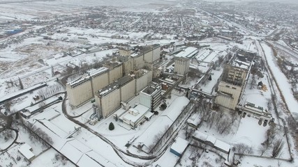 Grain terminal in the winter season. Snow-covered grain elevator in rural areas. A building for drying and storing grain