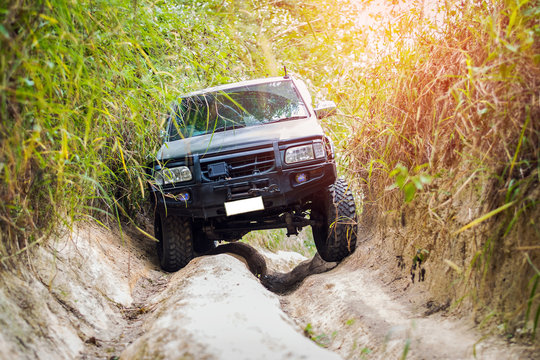 4 wheel drive with a motorcycle on the tailgate is climbing on a difficult off-road in mountain forests in Thailand.