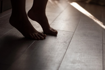 Woman's legs on a warm wooden floor
