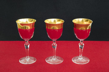 Golden glasses filled with a red liquid in red black background