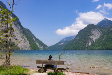 Person auf einer Bank vor Bergen und See