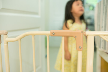 Close up safety gate on door and little girl crying.Baby protect fence,Stair gate.