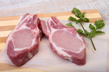 Raw pork chops, spices and basil on cutting board. Ready for cooking.