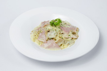 Spaghetti with ham and mushroom cream on white bowl and white Background