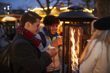 Group Of Friends Drinking Mulled Wine At Christmas Market