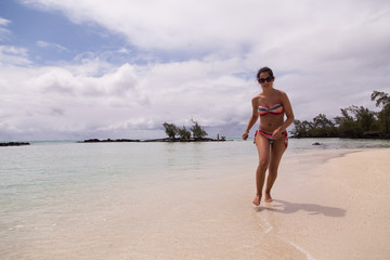 Woman running on beach deer island in mauritius islands