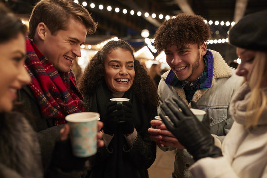 Group Of Friends Drinking Mulled Wine At Christmas Market