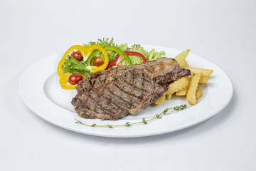 Rib Eye Steak served with fresh salad and french fried on white background