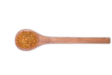 A pile of a yellow spice mix for on wooden spoon isolated on white background. Spices consist paprika onion garlic coriander turmeric black pepper basil dill