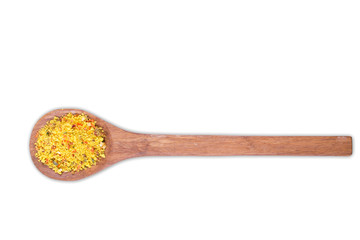 A pile of a yellow spice mix chicken bouillon. In wooden spoon isolated on white background. Spices consist dried dehydrated  vegetables carrot paprika onion garlic parsnip parsley