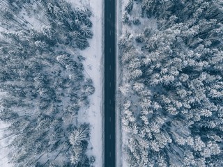 Country road going through the beautiful snow covered landscapes. Aerial view.
