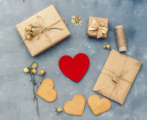 Flat lay Valentine's Day. Red heart sweets, gifts in craft paper, envelope on vintage background