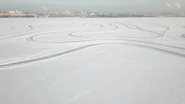 Winter landscape with tire trace on snow leaving to the horizon, sun and clouds in sky. Snow desert and the tracks of the car in the snow. Tracks on snow