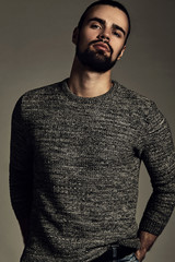 Fototapeta premium portrait of handsome fashion stylish hipster lumbersexual model dressed in warm sweater posing in studio. Metrosexual