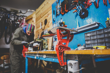 Naklejka premium A man in work clothes repairman in the workshop ski service repairing the sliding surface of the ski at Ski vise. In the hands of a tool. Theme ski repair and maintenance of equipment.