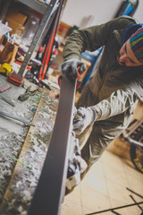 Male worker repairing Stone, edge sharpening in ski service workshop, sliding surface of the skis. sharpening of an edging of a mountain skis by means of the individual tool. Theme repair of ski curb