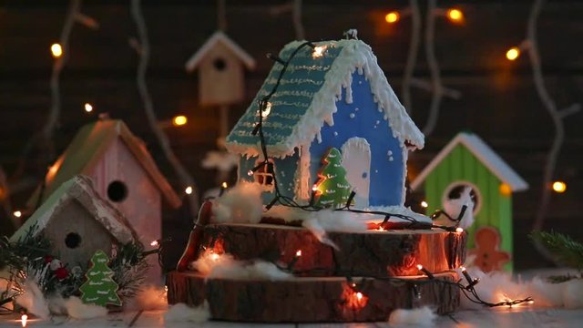 gingerbread house on the background of a garland and wooden houses. sprinkle with powdered sugar
