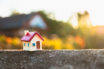 Closeup miniature house on sunset background using as property and family concept
