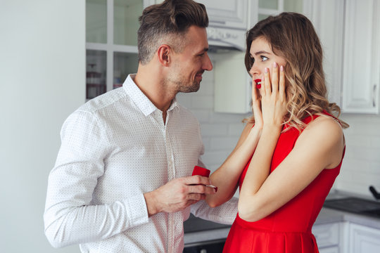 Young handsome man giving an engagement ring to his girlfriend at home