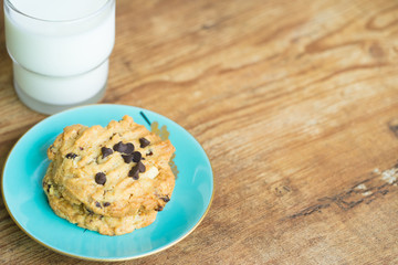 Chocolate chip cookies and glass of milk on old wooden table with place for text.freshly baked.