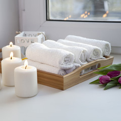 Obraz na płótnie Canvas the Rolled hand towels on a tray next to the lighted candles and a bouquet of tulips in the spa salon