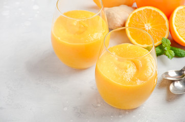 Fresh healthy smoothie with persimmon, orange and ginger on gray concrete background. Selective focus, copy space.